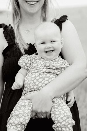 A series of black and white photos showing a smiling baby in a floral outfit being held by adults.