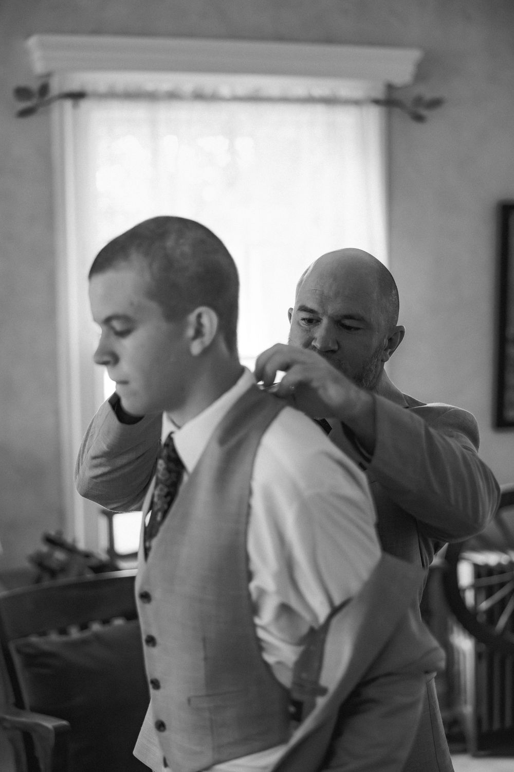 A sequence of black and white photos showing people helping each other get dressed for a formal occasion.