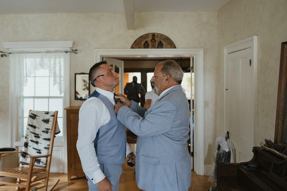 Two people in blue shirts dancing together in a bright white room with hardwood floors and large windows.