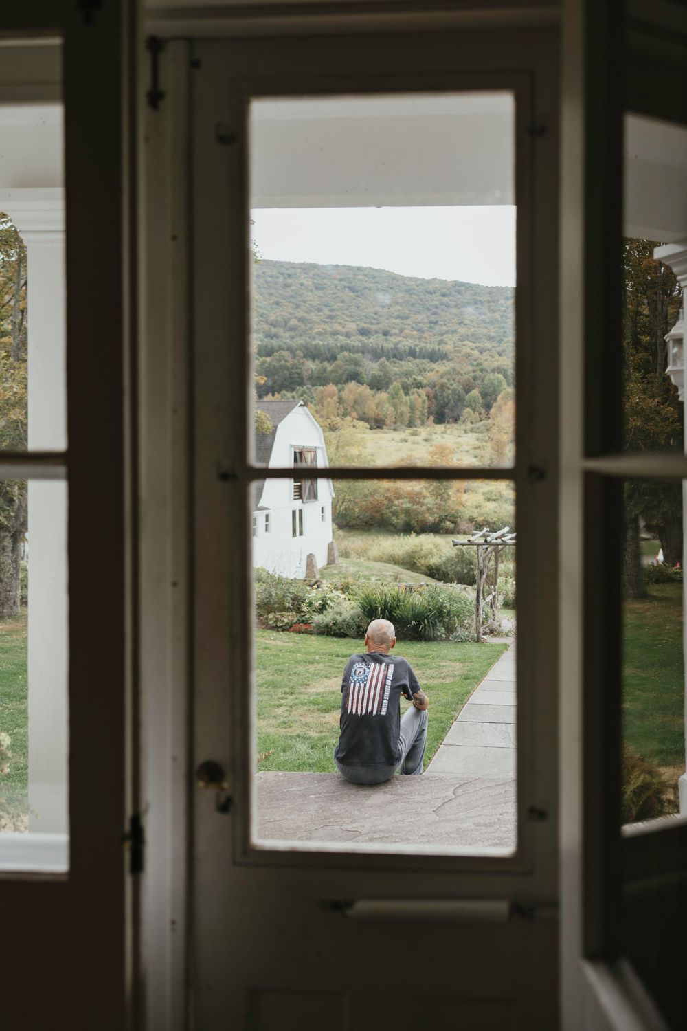 View through multiple window panes looking out at a rural landscape with rolling hills and greenery.