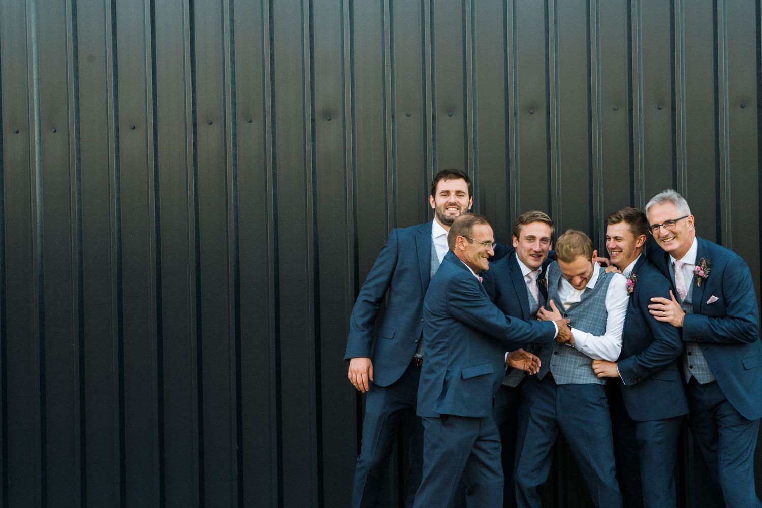 A group of people in navy blue suits pose together in a candid sequence of five connected photos.