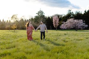 Couple attendant un bébé dans un champ au printemps avec lumière de fin de journée