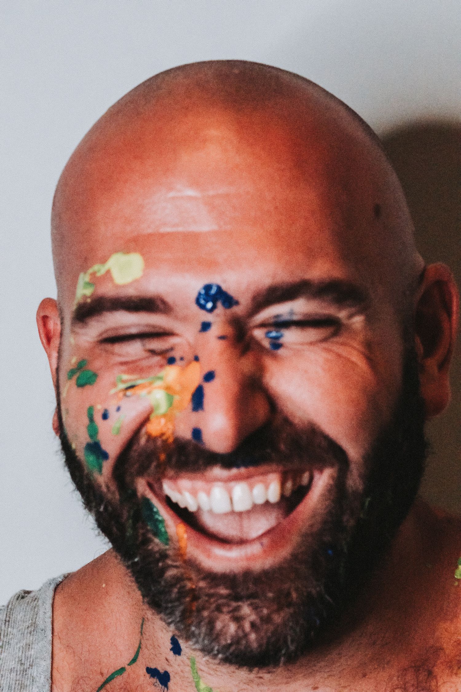 Close-up portrait of a joyful expression with colorful paint splattered across the face.
