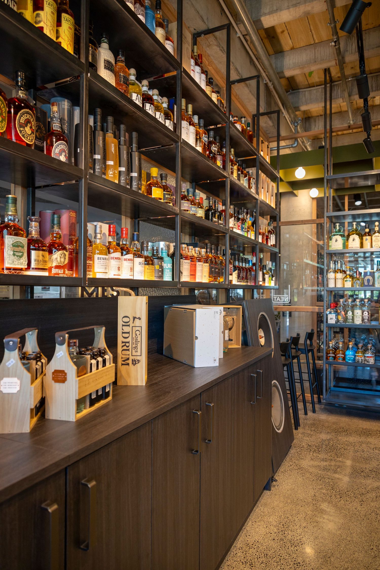 Liquor shelf filled with spirits at a modern bar with wood and metal finishes.