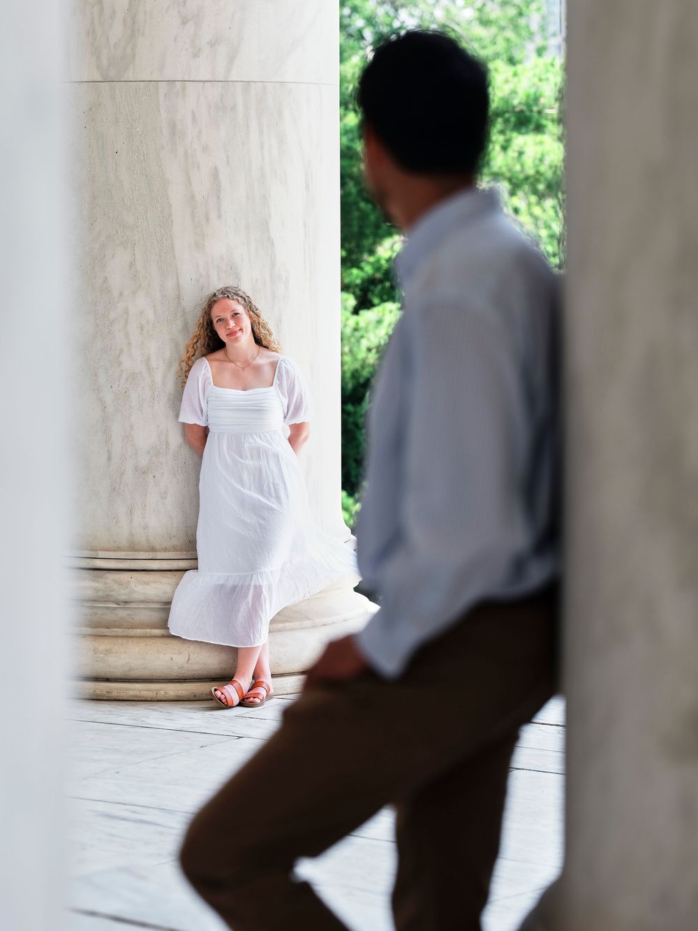 Man looking affectionately at woman during engagement session at Jefferson Memorial columns in Washington D.C.
