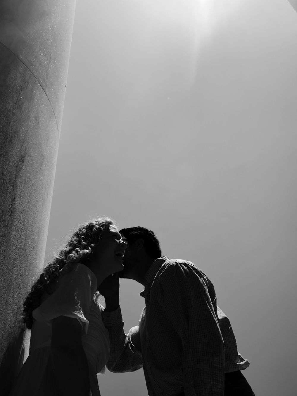 Romantic engagement photo of couple kissing between the columns at the Jefferson Memorial in DC.