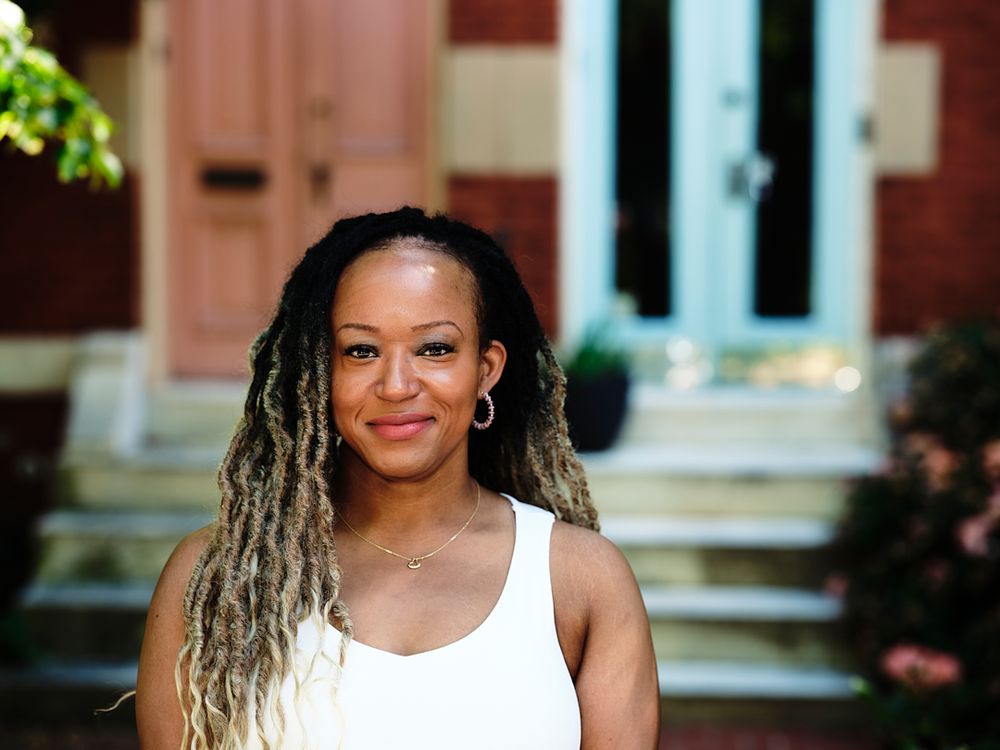 Environmental portrait of Airbnb host standing in front of rowhome in Peabody Heights, Baltimore.