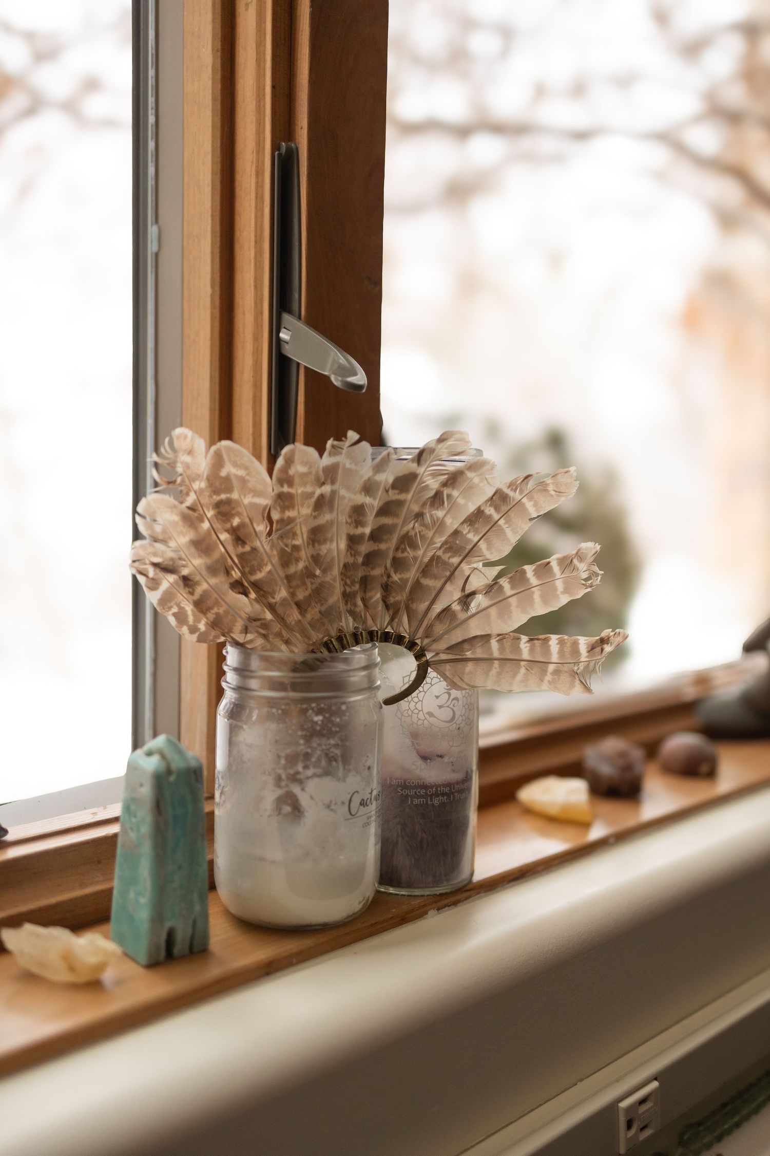 Feathers and crystals in a windowsill during sacred event photography.