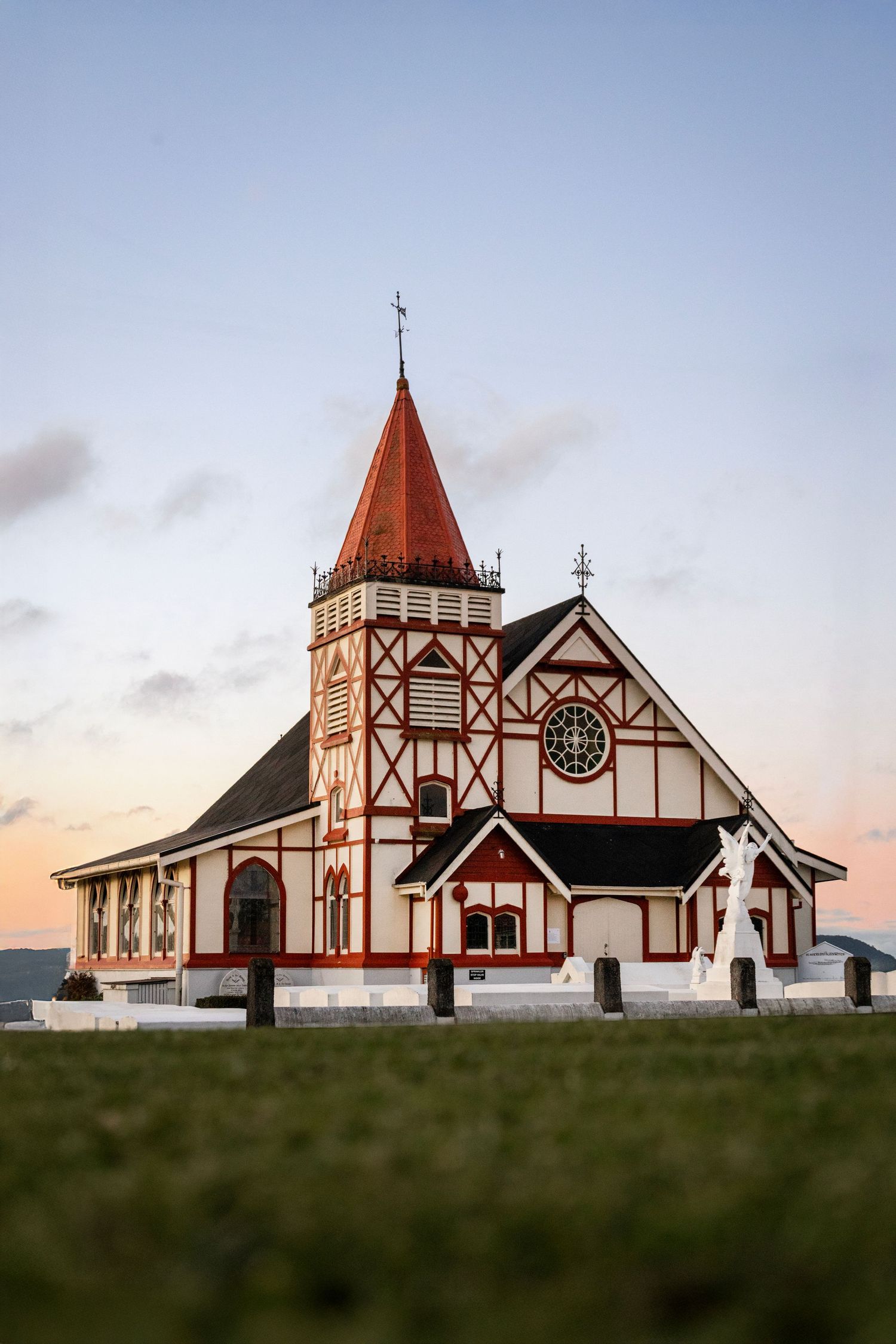 Historic Tudor-style Bath House building in Rotorua framed by pastel sunset sky and soft green lawn.