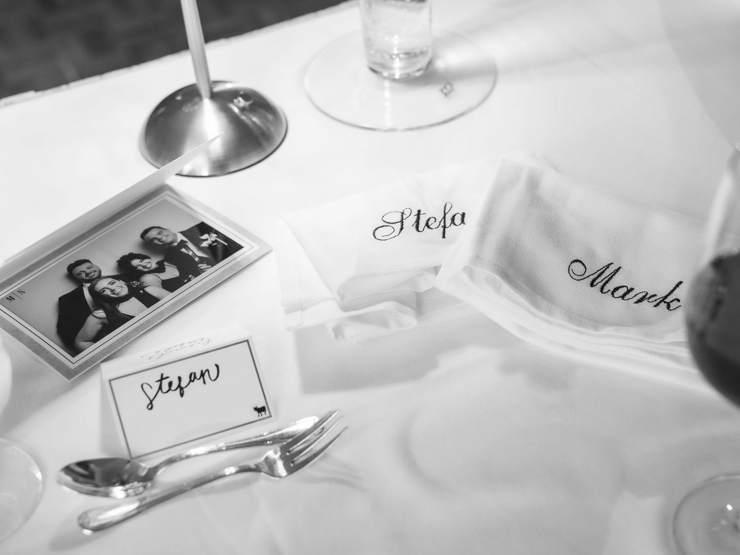 Black and white photograph of elegant table place settings with a photo booth print and name cards displayed