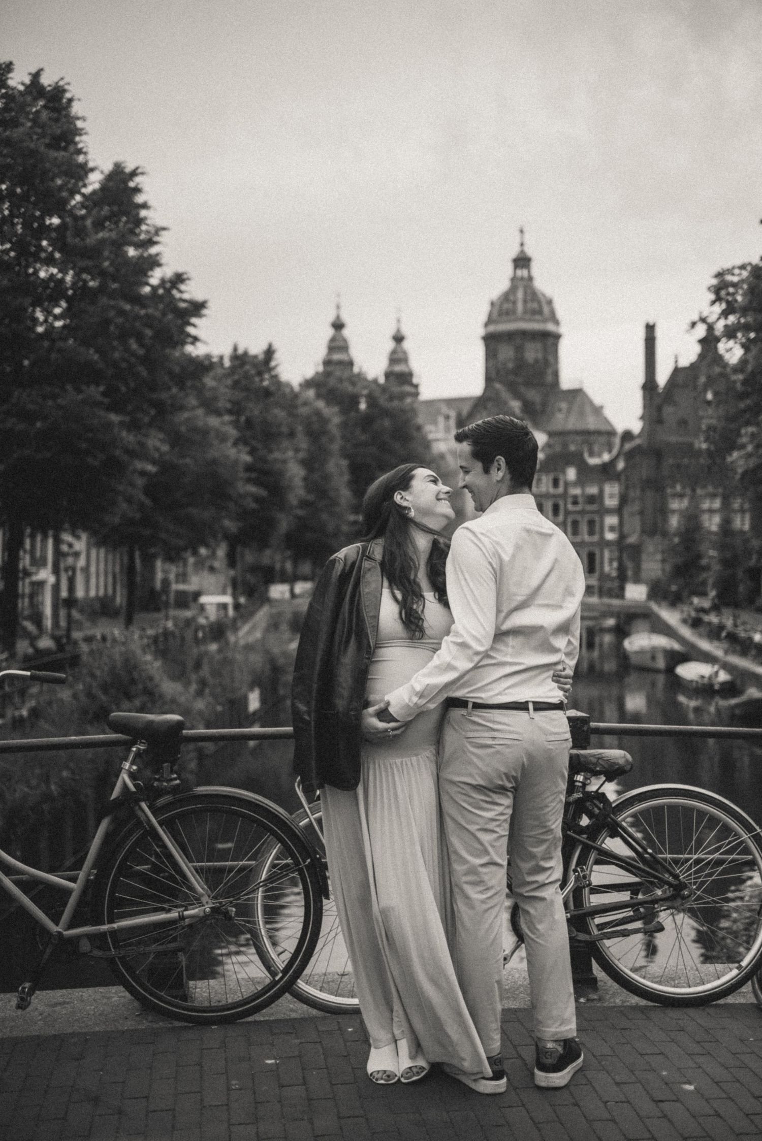 Black and white lifestyle photo of a pregnant couple by the canals of Amsterdam