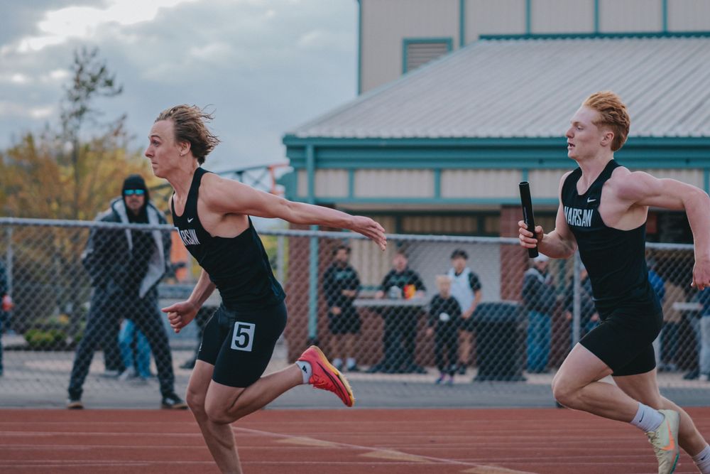 Sports Photography of athletes in uniforms passing batons during track and field relay race competition - Warsaw, Indiana