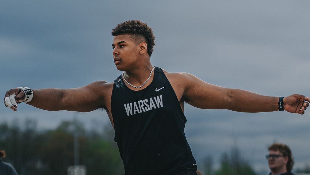 Sports Photography of Discus Athlete in Warsaw uniform performing shot put throw at outdoor track meet  - Warsaw, Indiana