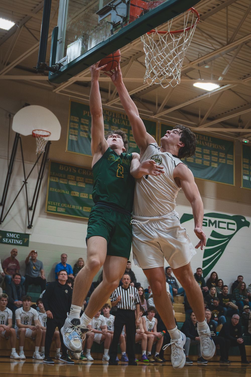 Sports Photography of two basketball players jumping high competing for a rebound under the hoop during an intense game - Monroe, Michigan