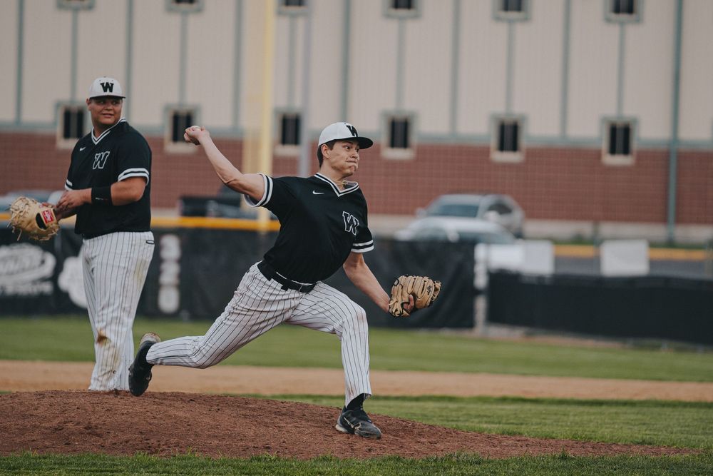 Sports Photography of baseball pitcher in black pinstripe uniform delivering pitch from mound during game - Warsaw, Indiana