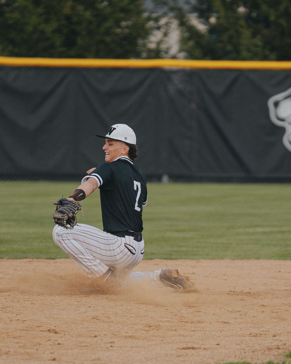 Sports Photography of baseball player sliding into base creating dust cloud during game - Warsaw, Indiana