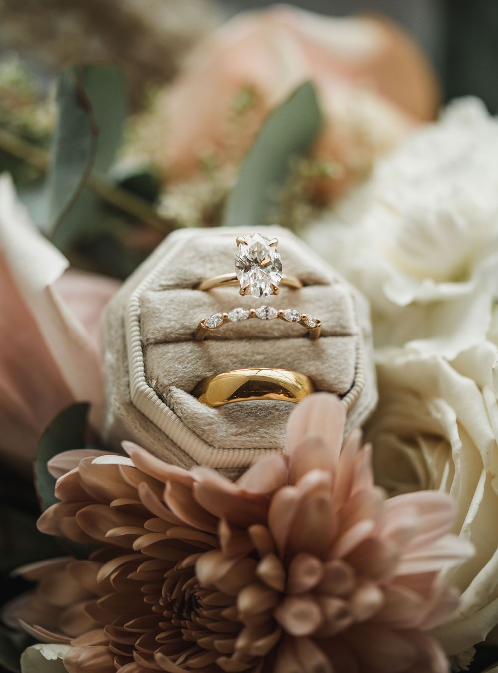 Close-up view of wedding rings nestled in delicate pink and white flowers with soft blurred background.