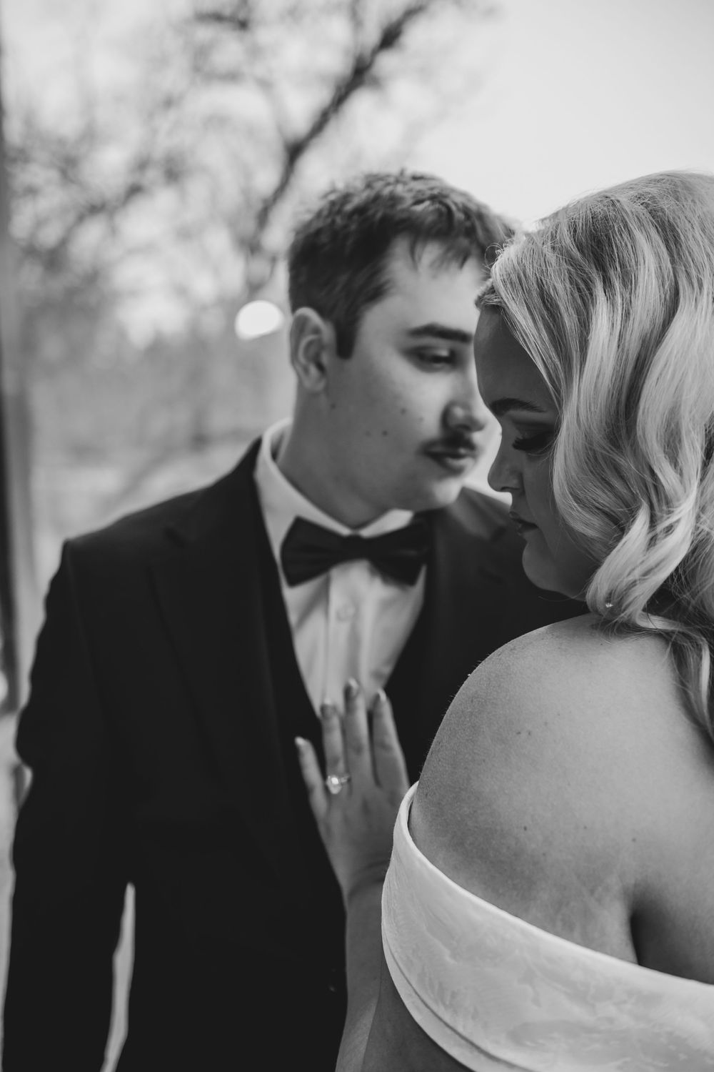 A romantic black and white photo series showing a couple in formal wedding attire sharing intimate close-up moments.