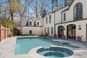 Luxurious white modern home features an elegant backyard with a geometric swimming pool and integrated spa. Real estate photography.