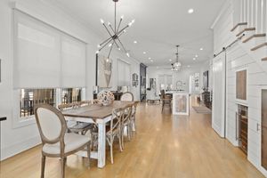 Bright, modern interior with white walls, hardwood floors, and sleek pendant lighting along a clean corridor. Real estate photography.