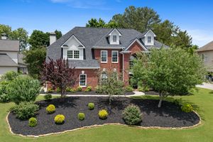 Elegant two-story brick colonial house with professionally landscaped front yard. Real estate photography.
