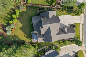 Aerial drone view of a modern gray roof home with manicured lawn and landscaping in a residential neighborhood. Real estate photography.