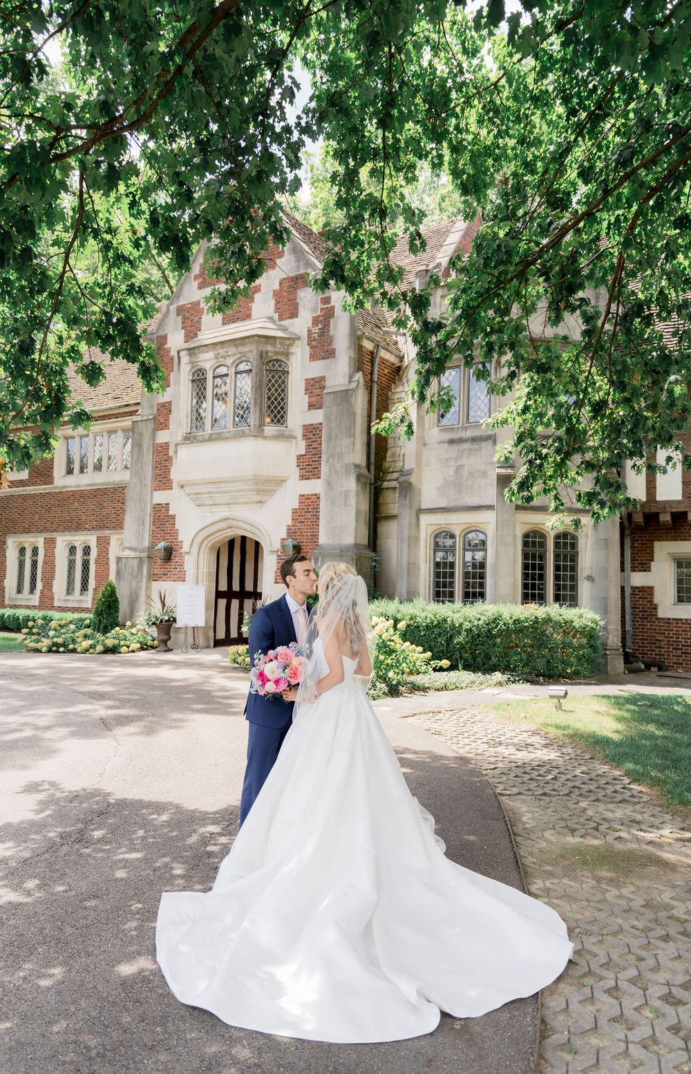 A romantic wedding photo series showing a couple in formal attire dancing on stone pavers near a historic brick building.