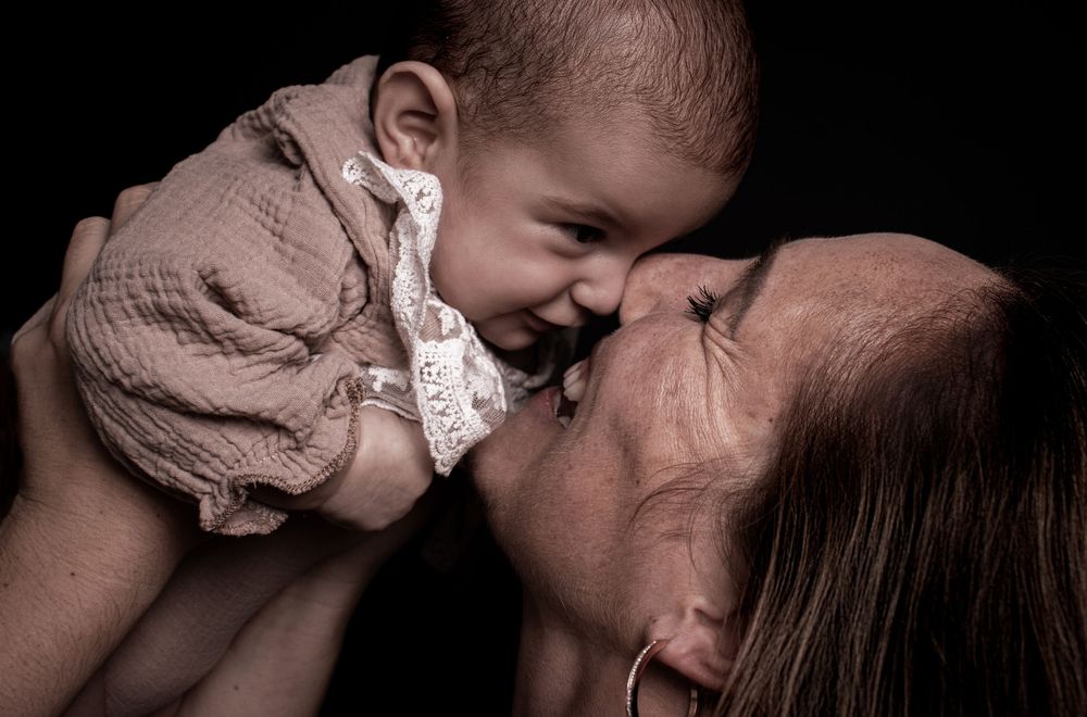 A tender moment between a parent and a baby sharing laughter and nose-to-nose contact.