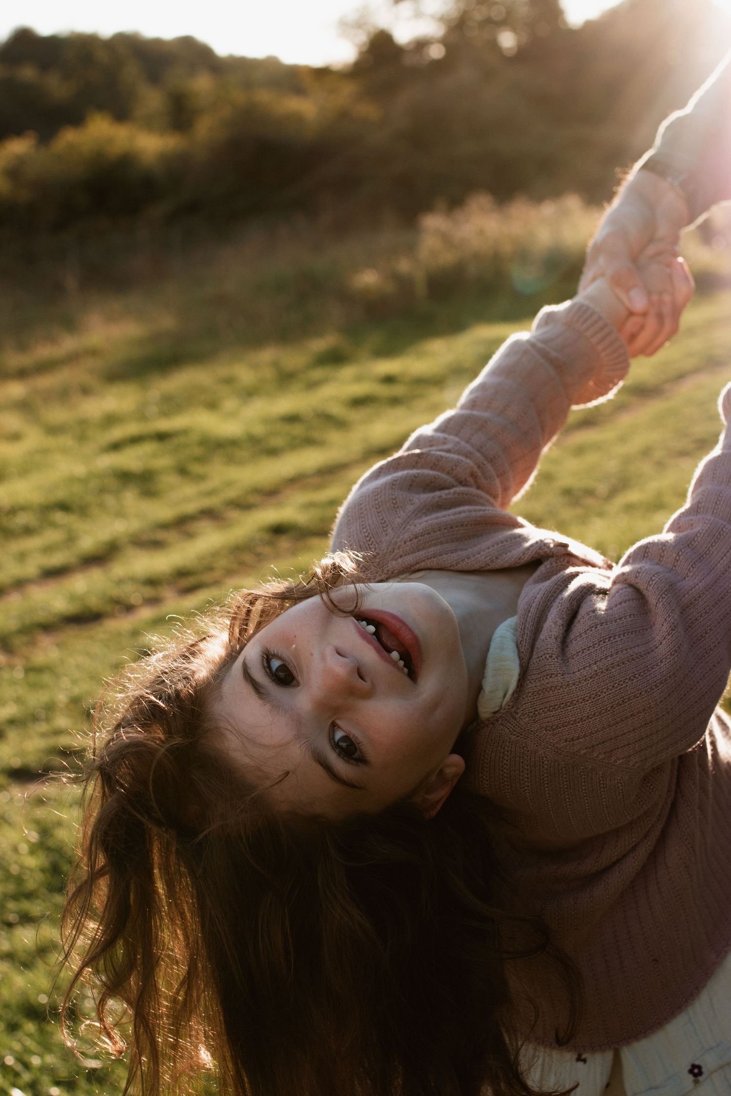 Candid lifestyle photos taken at sunset in a grassy field with warm golden lighting.