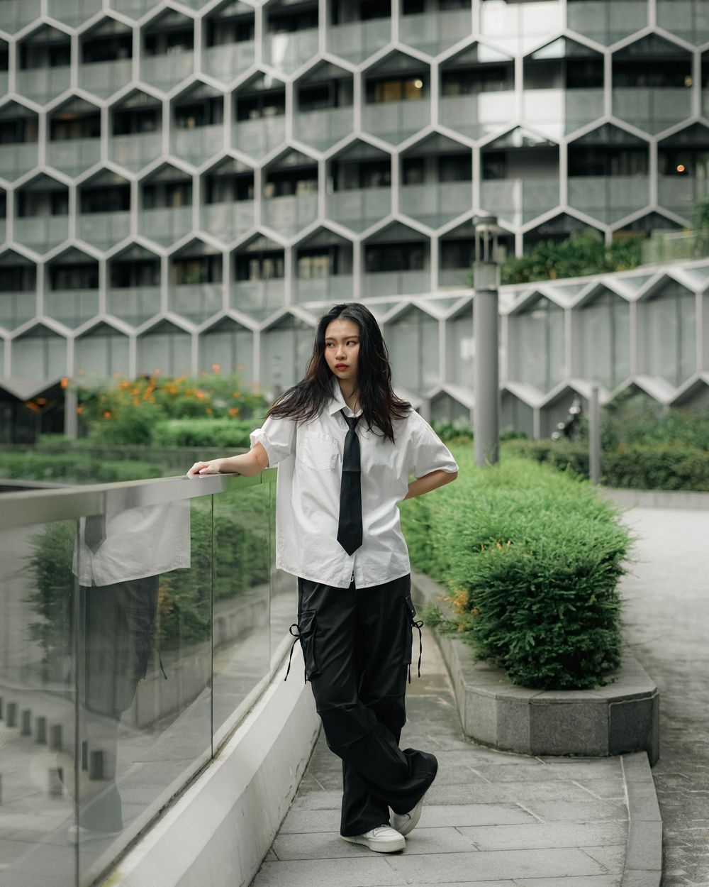Modern office building with hexagonal facade architecture and green landscaping features on a rainy day.
