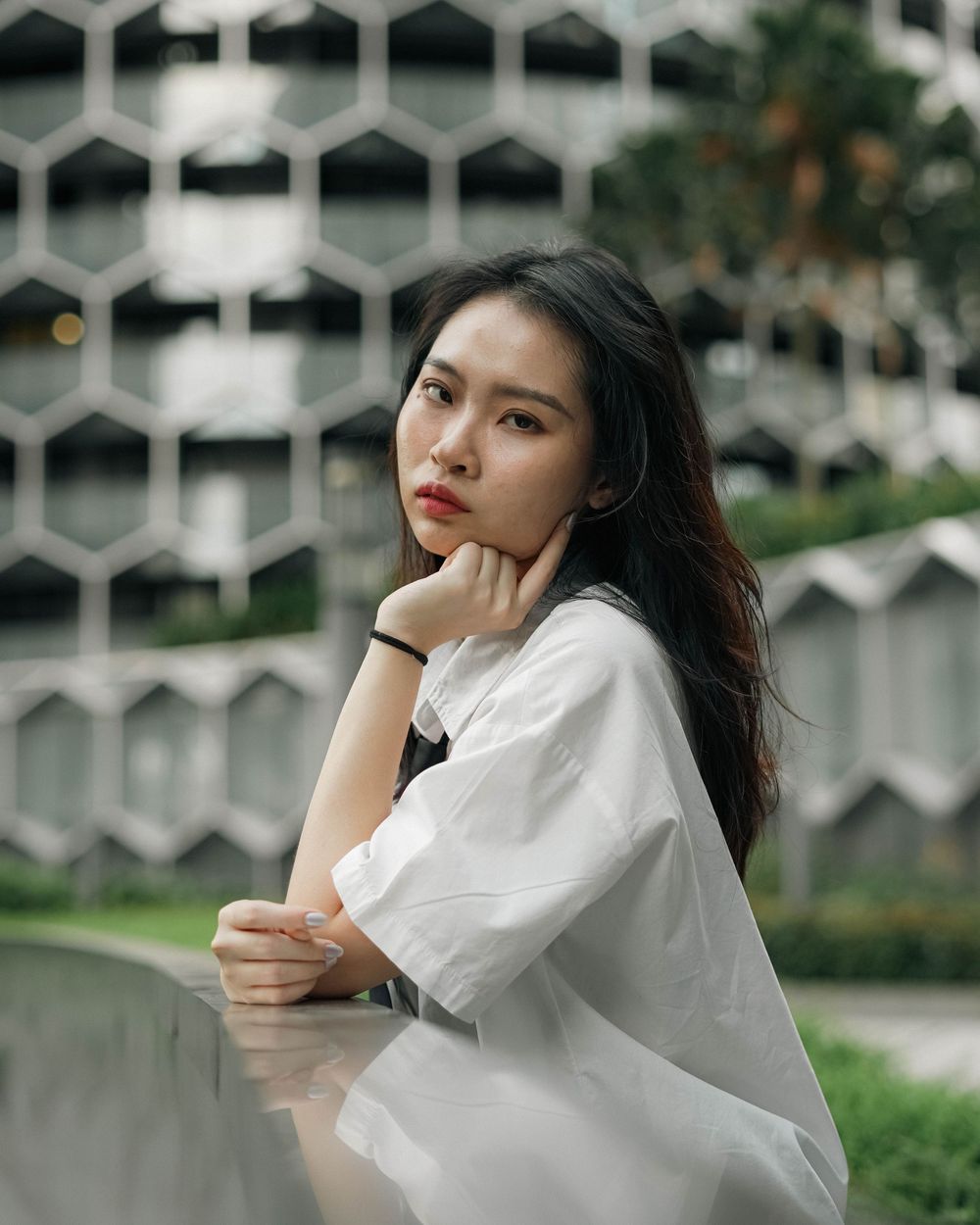 Person in white button-down shirt poses thoughtfully against geometric architectural background with honeycomb pattern.