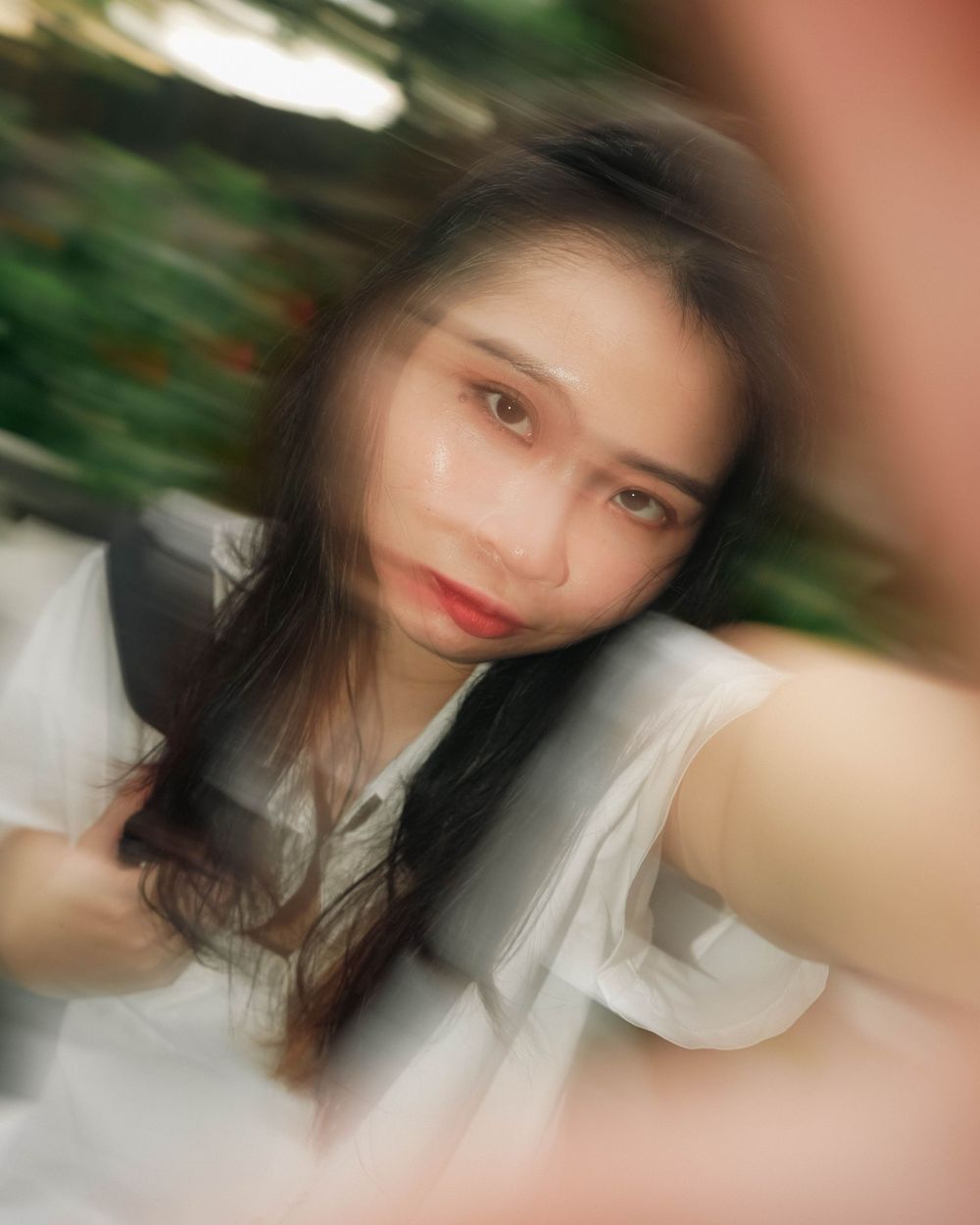 Dreamy selfie portrait with soft focus effect showing person in white outfit against blurred natural background.