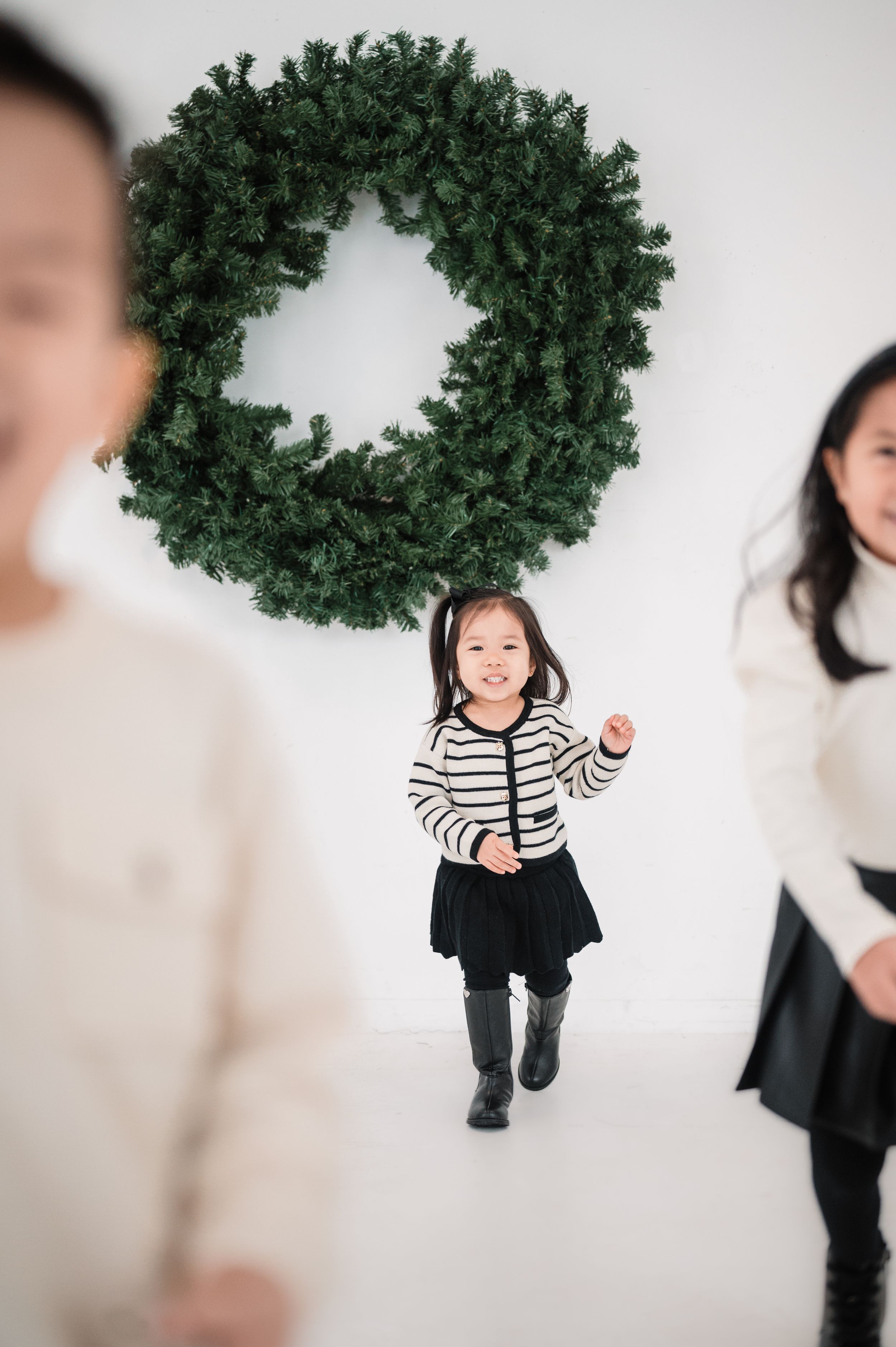 Holiday family portraits with evergreen wreath decoration in studio setting.