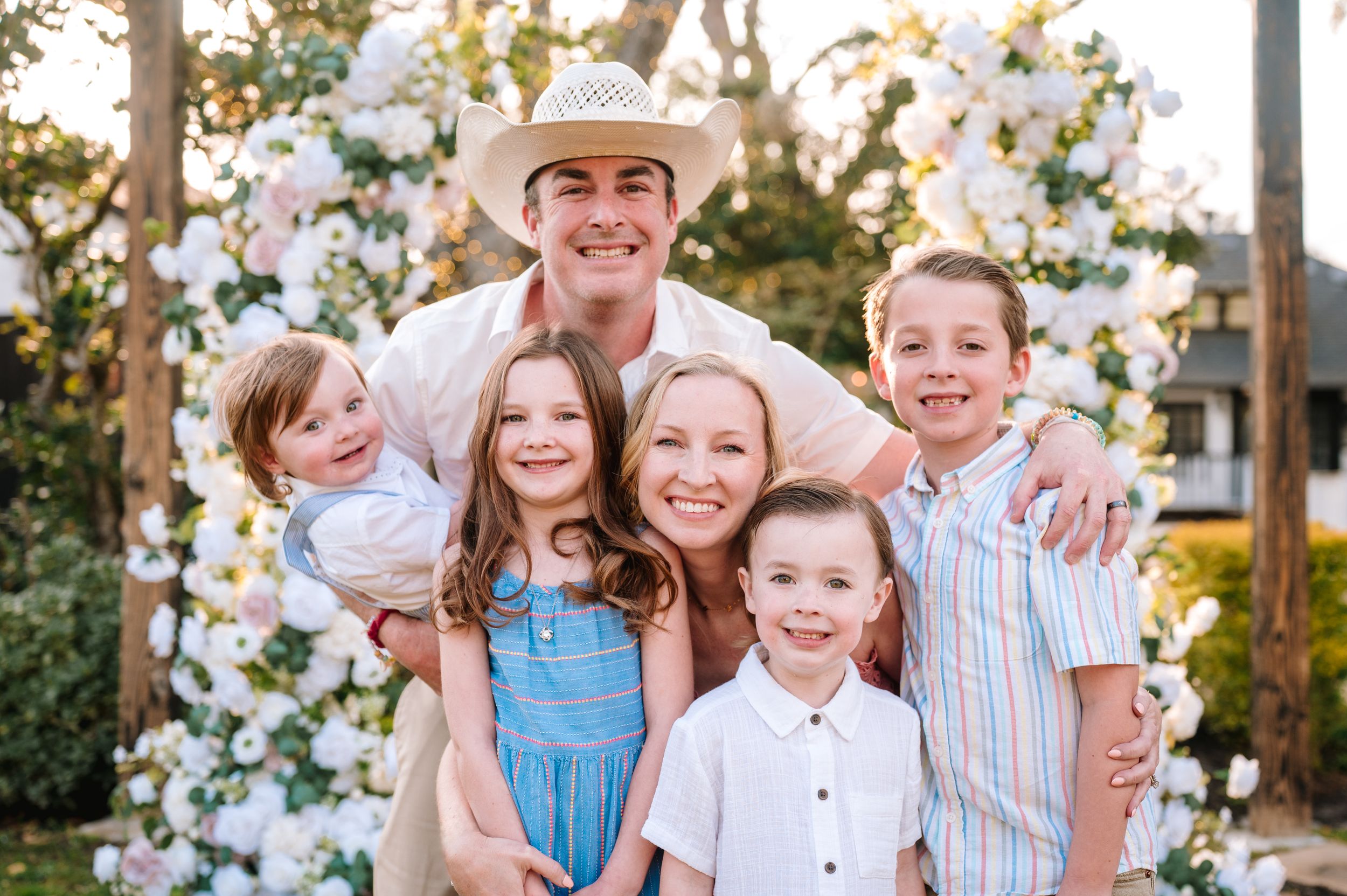 Family group smiles together outdoors in coordinated casual outfits.