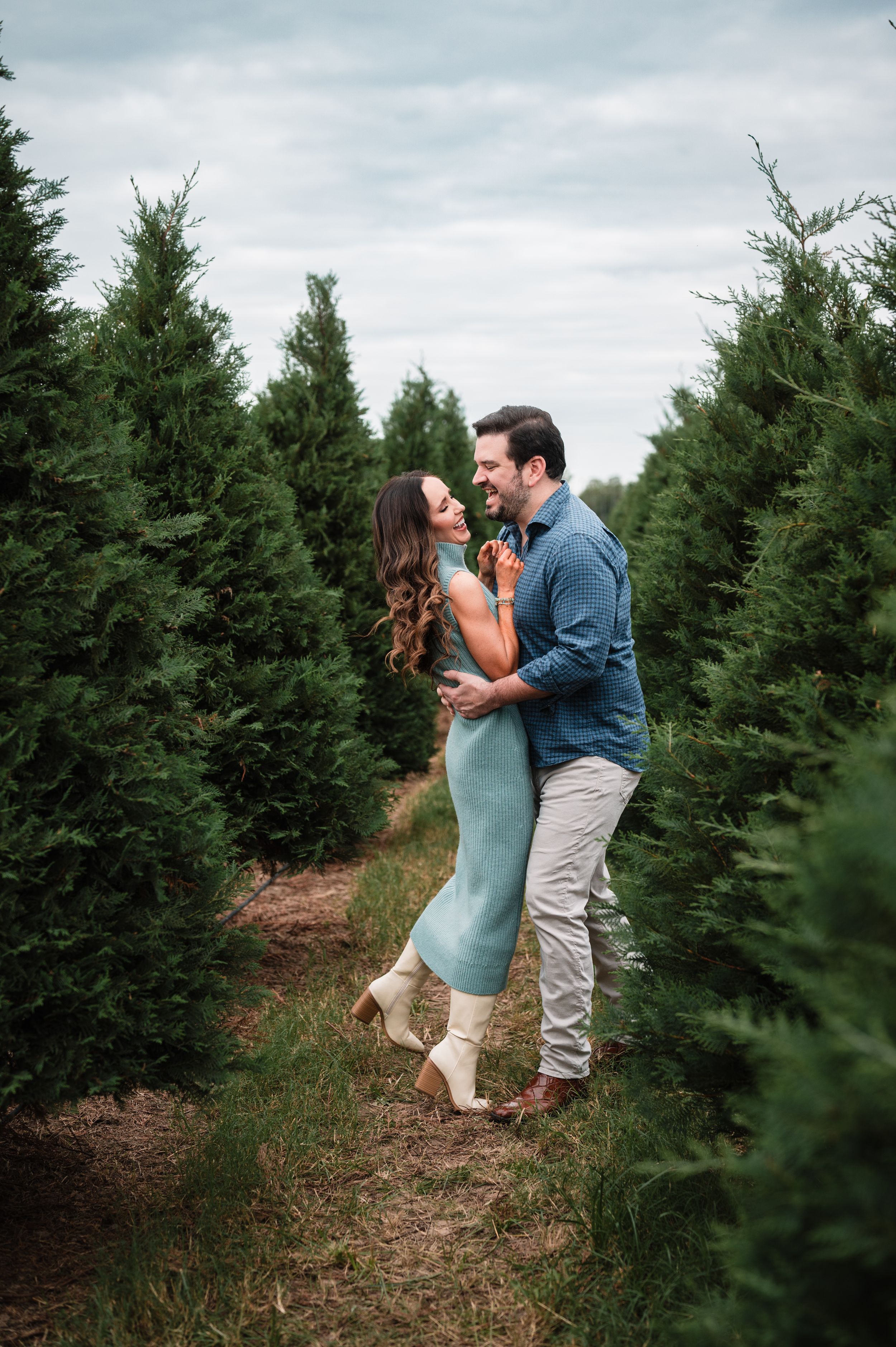 A romantic couple sharing a playful moment in an evergreen tree farm.