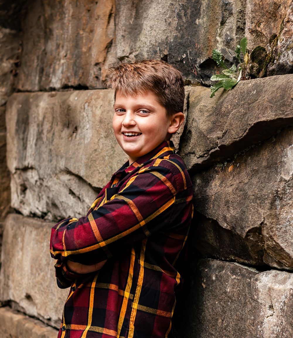 Candid photo session against a textured rock wall backdrop with warm autumn lighting.