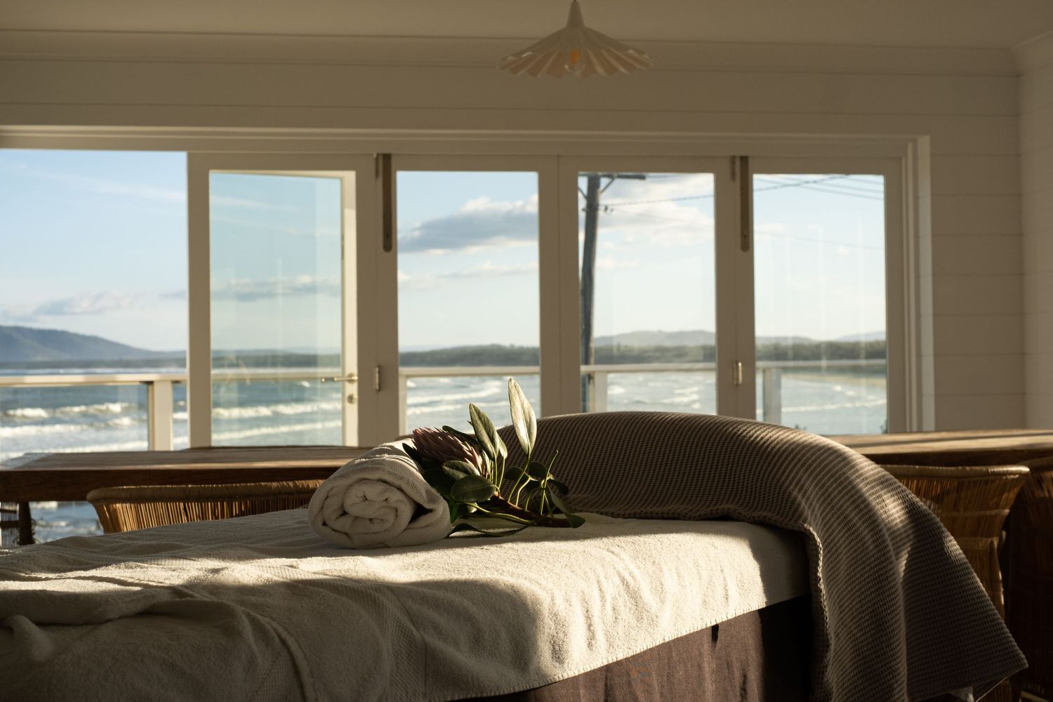 Serene bedroom with large windows showing stunning mountain and ocean vistas.