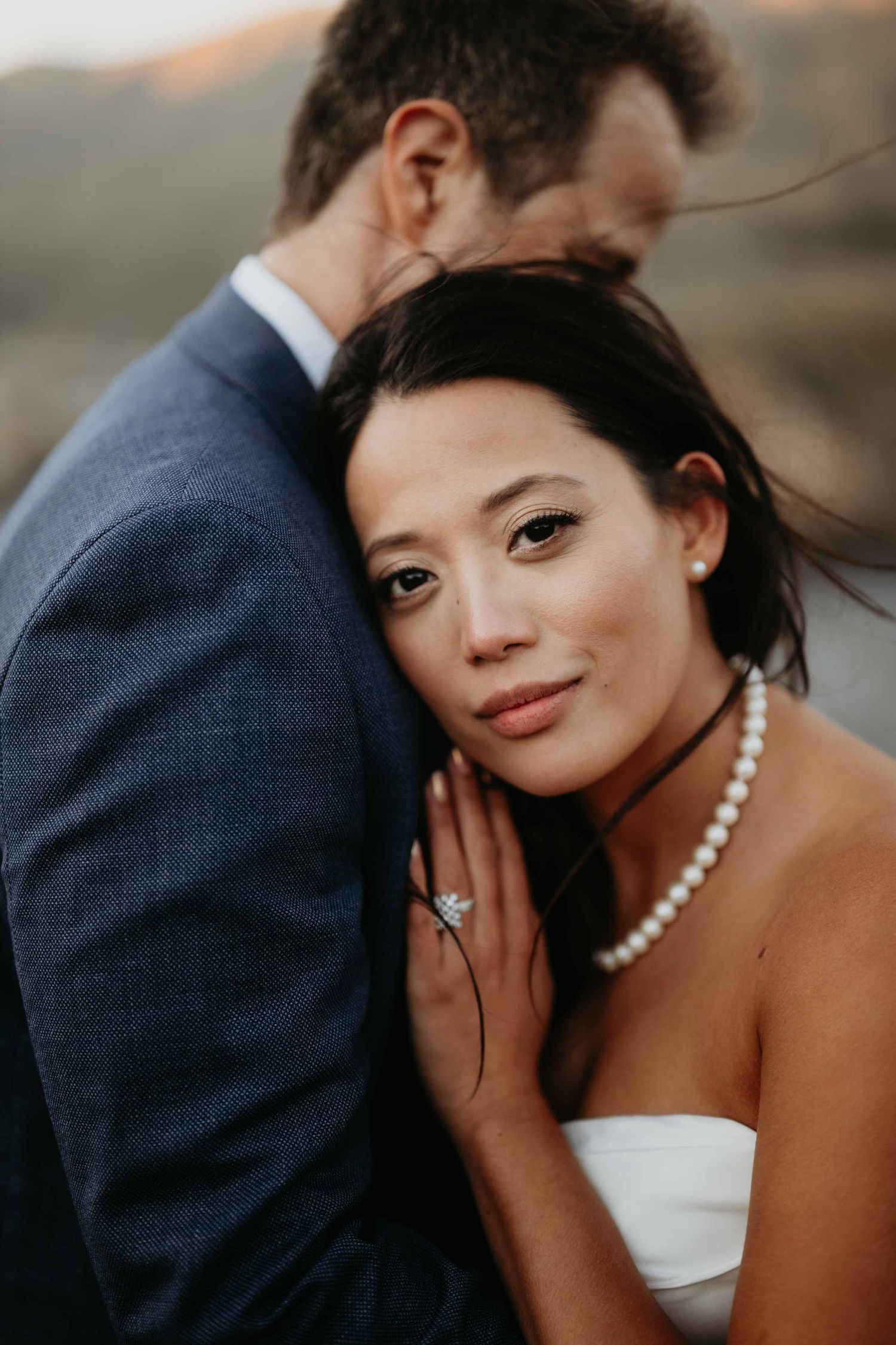 groom gently holding his bride and she looks into the camera soft and romantic