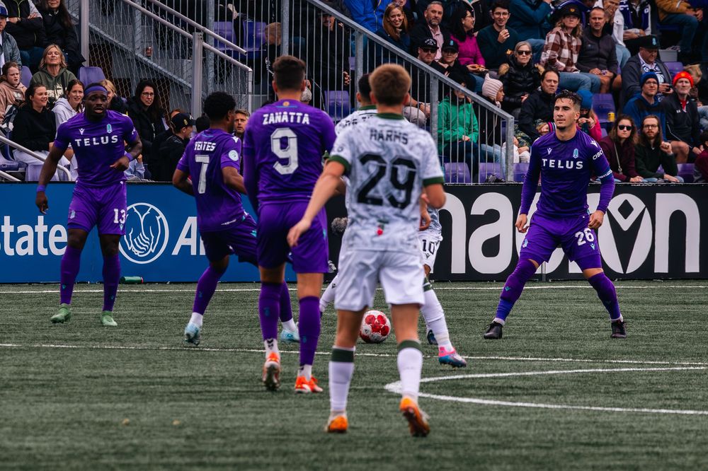 Soccer players compete for possession during an intense match on an artificial turf field.