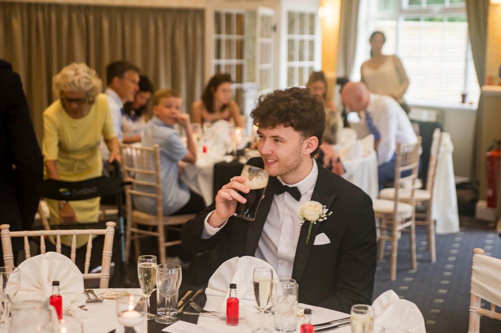 Wedding reception guests seated at elegant tables in a bright banquet hall with formal place settings.