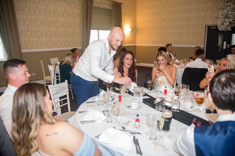 Wedding guests enjoying a formal dinner reception at elegantly decorated round tables.