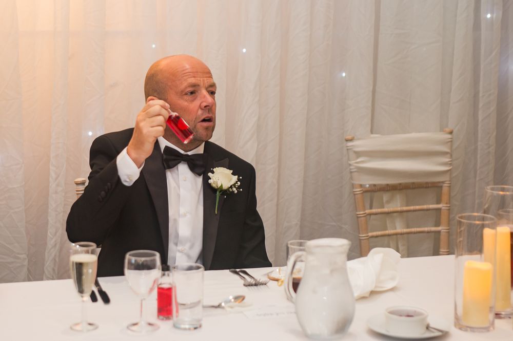 Wedding reception guests dining and socializing at formal tables with white linens.