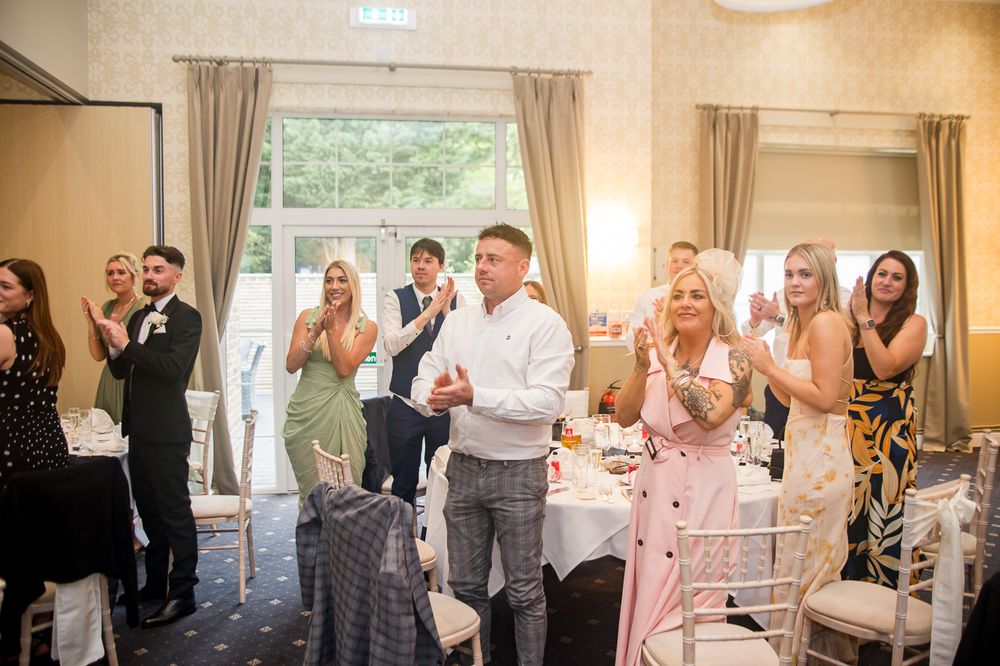 Wedding guests celebrating and applauding during reception festivities.