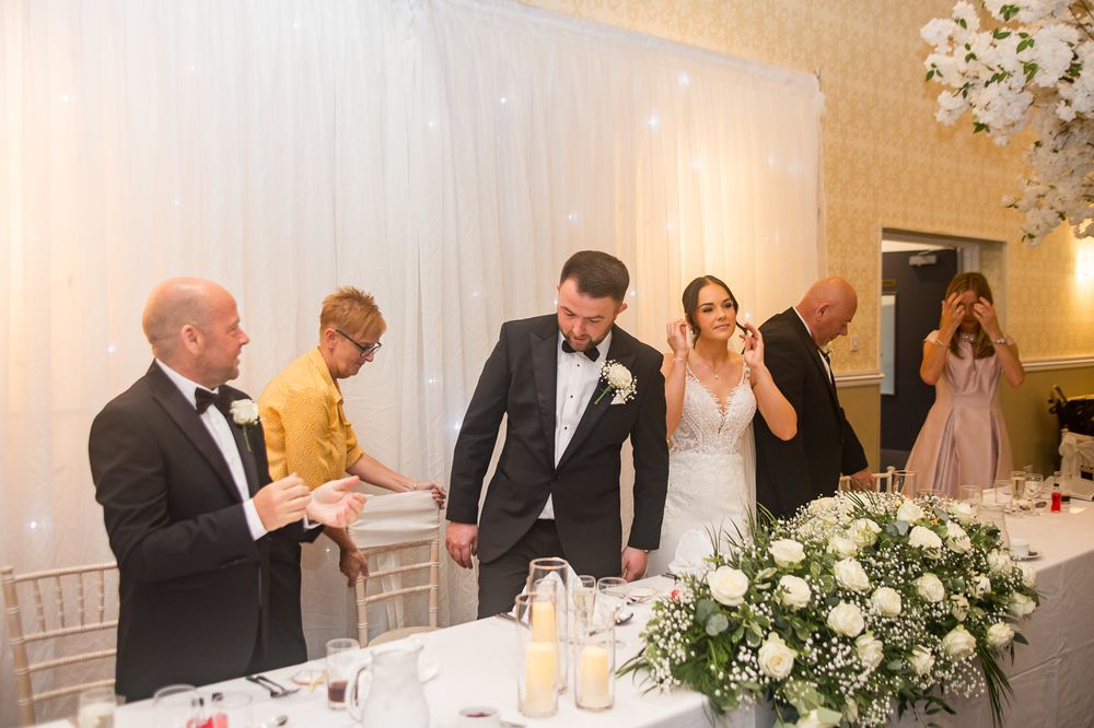 Wedding reception guests celebrating and clapping during formal dinner festivities.