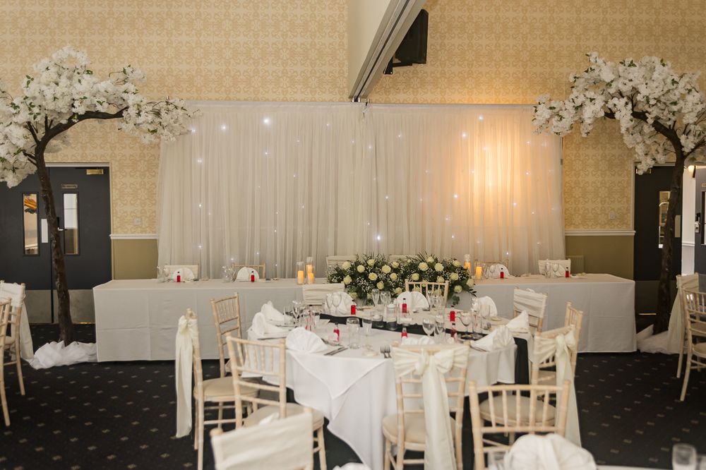 Wedding reception hall decorated with white linens and cherry blossom floral arrangements.