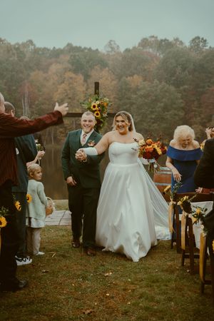 Wedding guests celebrate outdoors in autumn with sunflowers and fall foliage in the background.