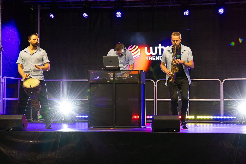 Stage performers illuminated by blue spotlights entertain an audience during a live concert performance at the WTM in the ExCel, London.