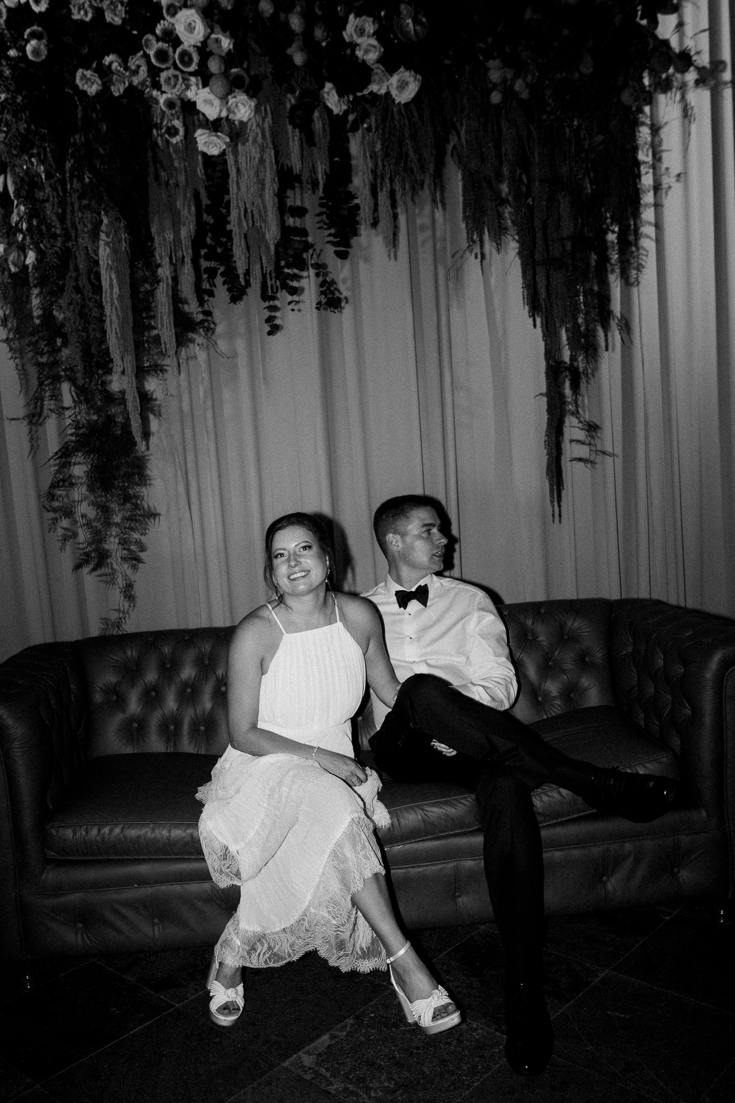 A dramatic black and white photo series showing figures in white dresses creating artistic poses on dark furniture.