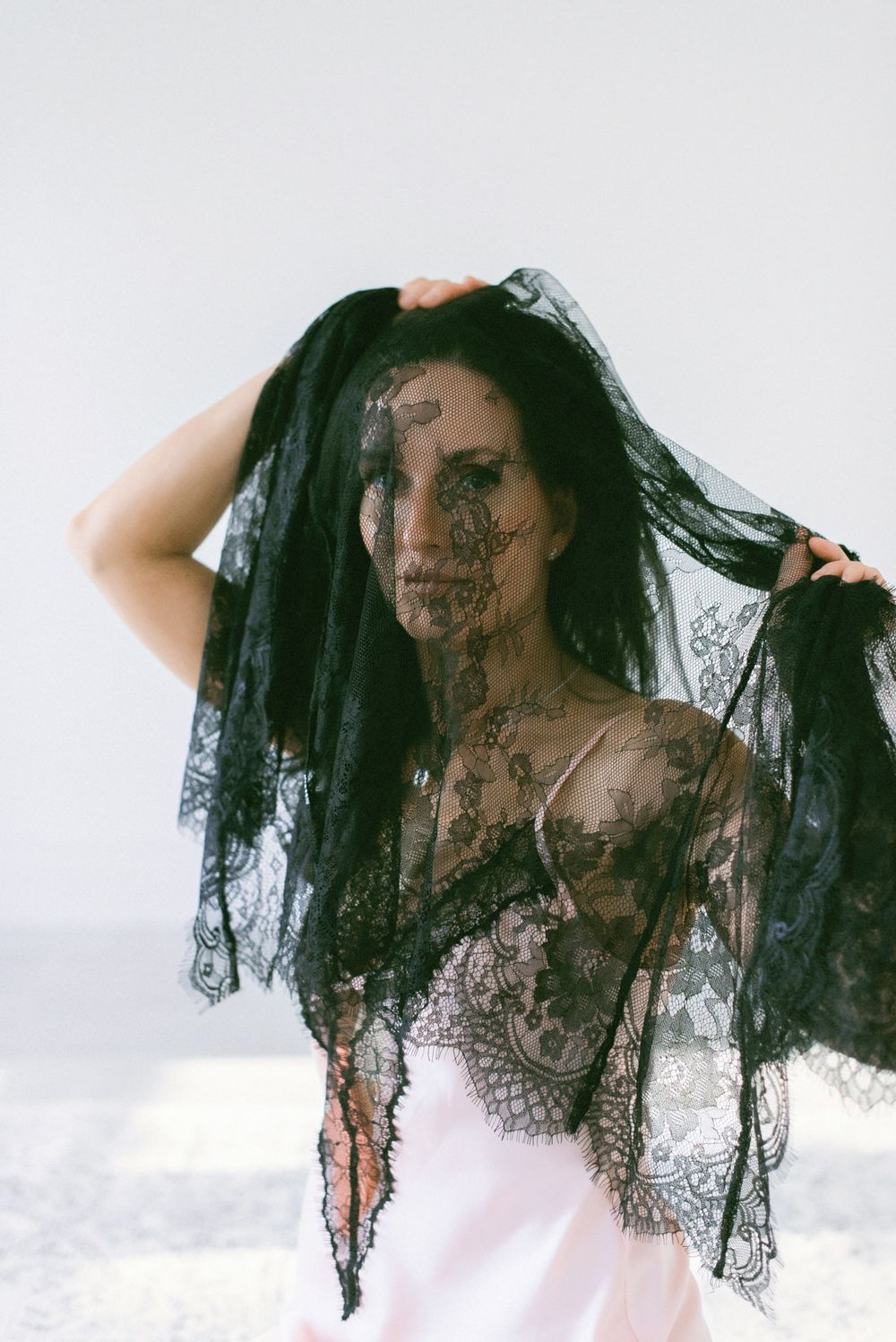 A sequence of artistic photos showing a person draped in flowing black lace veil against a white background.
