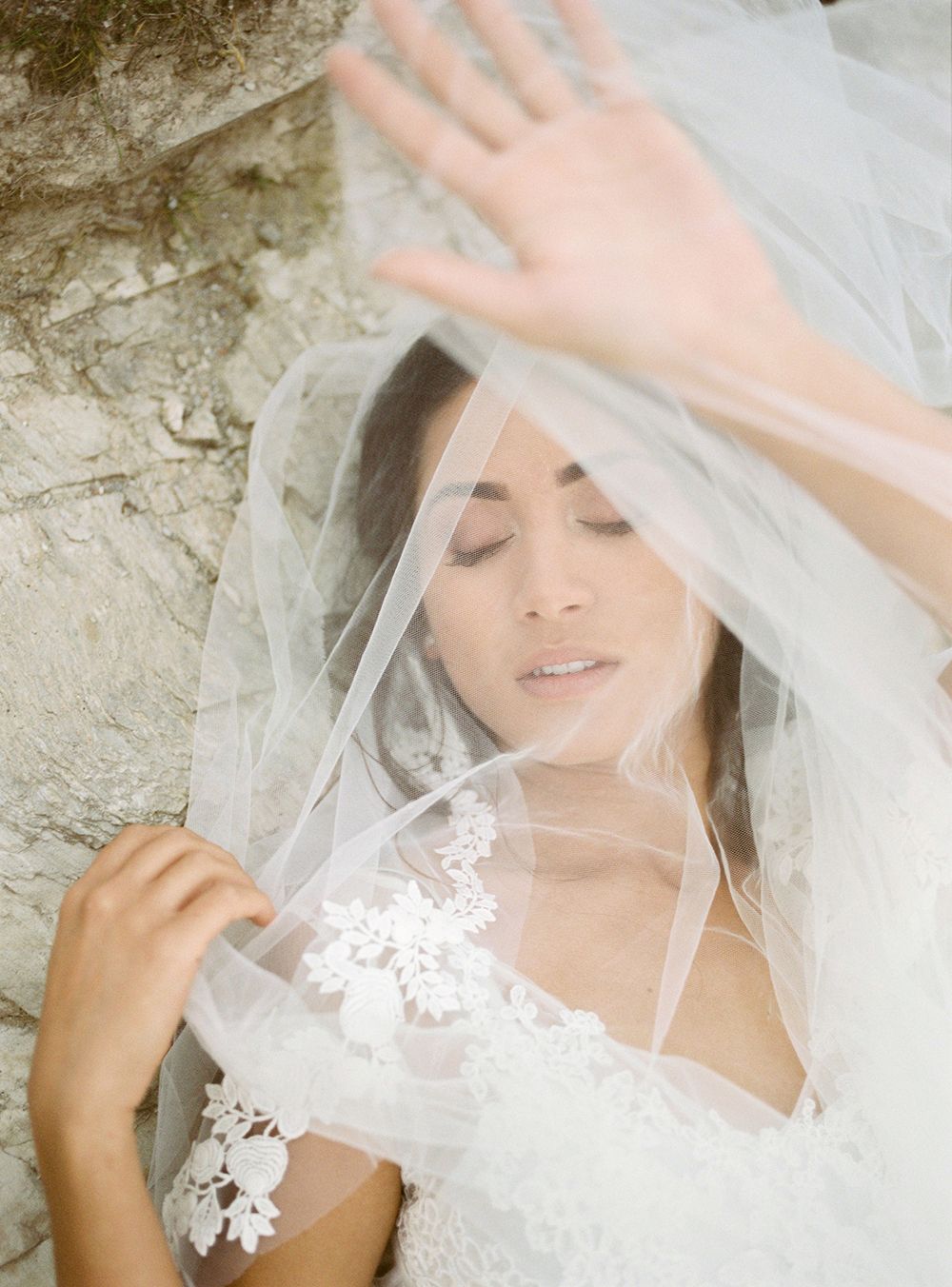 A bride in a delicate lace veil poses in a series of romantic bridal portraits with soft, ethereal lighting.